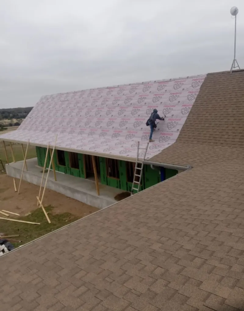 Worker preparing underlayment for a metal roof installation in Somerton